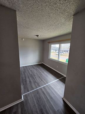 Hughes Springs house for rent - A room with grey flooring and a window overlooking a parking lot.