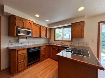 Longview house for rent - A kitchen with wooden cabinets and a black stove top.