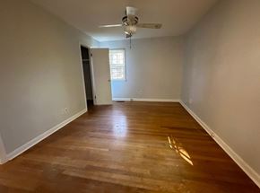 Fayetteville house for rent - an empty living room with wooden floors and a ceiling fan