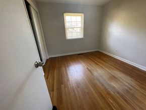 Fayetteville house for rent - an empty room with wooden floors and a window
