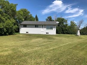 Prince Albert house for rent - A white house with a grey roof is surrounded by a grassy field.