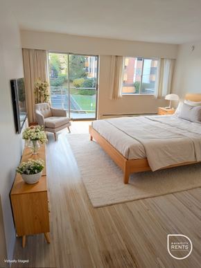 New Westminster apartment for rent - A bedroom with a large bed and a chair by the window.