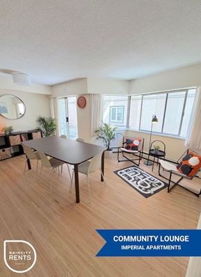 New Westminster apartment for rent - A community lounge area with a table, chairs, and a rug in a room with wooden flooring and white walls.