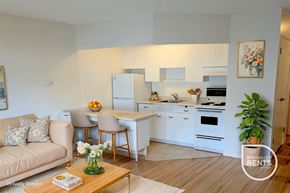 New Westminster apartment for rent - A well-lit kitchen with white cabinets and a dining table with chairs.