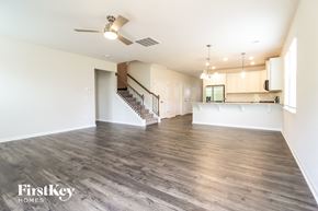 Greenville house for rent - an empty living room and kitchen with wood flooring and a ceiling fan