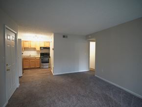 Louisville apartment for rent - A room with a carpeted floor and a doorway leading to a kitchen.