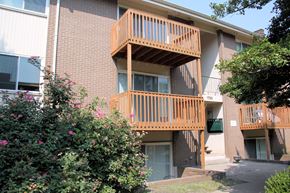 Louisville apartment for rent - Apartment building with a balcony and bushes in front.