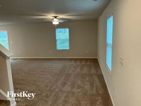 Charlotte house for rent - an empty living room with a ceiling fan and windows
