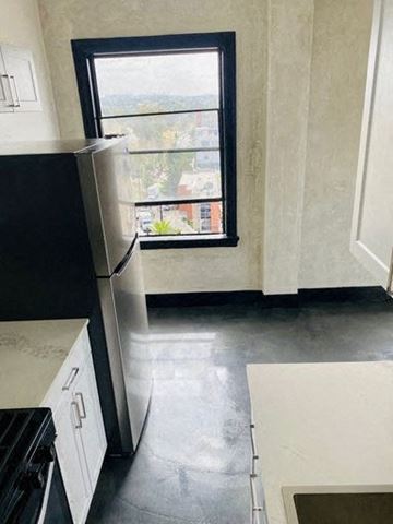 Los Angeles apartment for rent - A black refrigerator in a kitchen with a window.