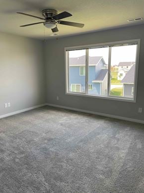 Urbandale house for rent - an empty living room with a ceiling fan and a large window