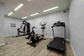 Saskatoon apartment for rent - A gym with a treadmill, elliptical trainer, and stationary bike.