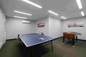 Saskatoon apartment for rent - A ping pong table is in the middle of a room with a pool table on the other side.