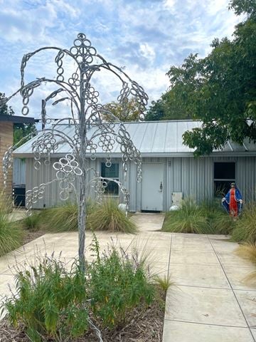 San Antonio house for rent - A metal tree sculpture is in the foreground of a building with a grey roof.
