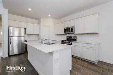 Fort Worth house for rent - A kitchen with white cabinets and a stainless steel refrigerator.