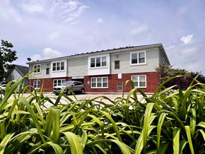 Trenton apartment for rent - A house with a grey and red exterior is surrounded by green plants.