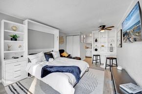 Melbourne apartment for rent - A bedroom with a bed, a ceiling fan, and a painting on the wall.