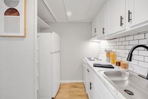 Melbourne apartment for rent - A kitchen with white cabinets and a white fridge.
