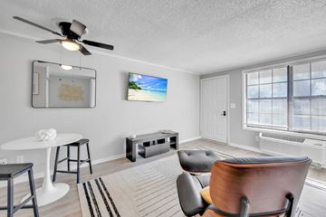 Melbourne apartment for rent - A living room with a ceiling fan, a white table, a black chair, and a painting on the wall.