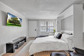 Jacksonville apartment for rent - A bedroom with a large bed and a flat screen TV mounted on the wall.