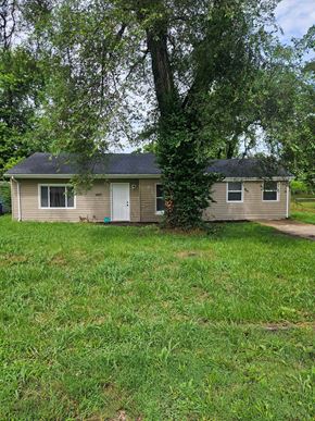 St. Louis house for rent - A small house with a white door and a window is surrounded by green grass.