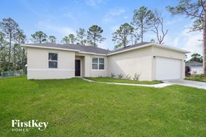 Palm Bay house for rent - a white house with a grassy yard and a garage