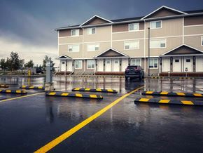 Regina apartment for rent - A car is parked in a parking lot in front of a building.
