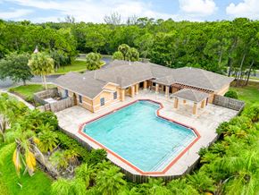 Port St Lucie apartment for rent - A large house with a pool surrounded by trees.