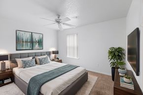 Port St Lucie apartment for rent - A bedroom with a bed, a ceiling fan, and a painting on the wall.