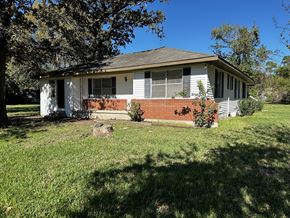Conroe apartment for rent - a small white house with a lawn and trees