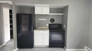 Cincinnati apartment for rent - A black refrigerator and oven in a kitchen with white cabinets.