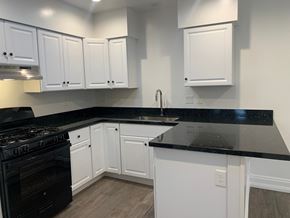 Goleta apartment for rent - A kitchen with white cabinets and black countertops.