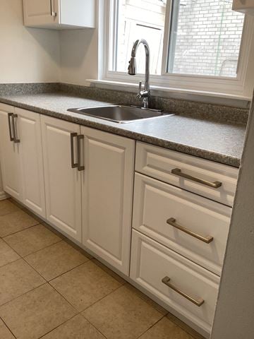Brampton apartment for rent - a kitchen with white cabinets and a sink and a window