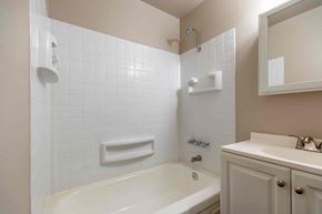 Vancouver apartment for rent - A white bathtub with a shower head and a white sink with a mirror above it.