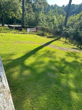 Fayetteville house for rent - A grassy field with a fence and trees in the background.