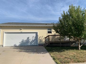 Kearney house for rent - a yellow house with a garage door and a tree