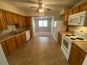 Fayetteville house for rent - a kitchen with white appliances and wooden cabinets