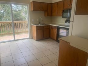 Pensacola house for rent - an empty kitchen with a sliding glass door to a balcony