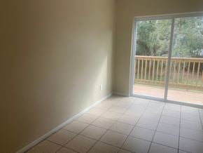 Pensacola house for rent - an empty living room with a sliding glass door to a balcony