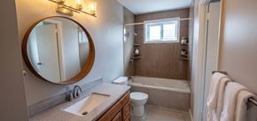 Trenton apartment for rent - A bathroom with a round mirror, a sink, a toilet, and a bathtub.