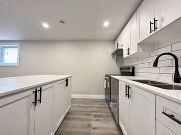 Trenton apartment for rent - A kitchen with white cabinets and a black faucet.