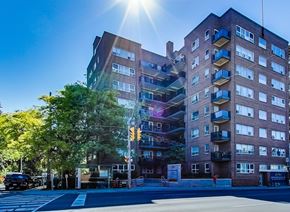 Toronto apartment for rent - A sunny day in front of a multi-story building with a street in front.