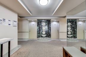 Toronto apartment for rent - A hallway with three doors on the right and a white bench on the left.