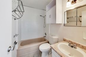 Don Mills apartment for rent - A white toilet sits under a mirror in a bathroom.