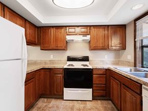 Vancouver apartment for rent - A kitchen with a white fridge, black stove and wooden cabinets.