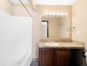Vancouver apartment for rent - A bathroom with a sink, mirror, and wooden cabinets.