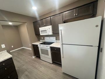 Dodge City apartment for rent - A white refrigerator stands in a kitchen with a microwave, oven, and sink.
