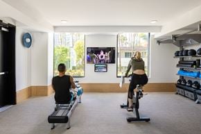 San Diego apartment for rent - a man and a woman riding bikes in a gym and watching a tv screen