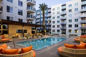 San Diego apartment for rent - a swimming pool with orange chairs in front of an apartment building
