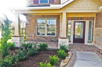 Cypress house for rent - a front porch of a brick house with a walkway and plants