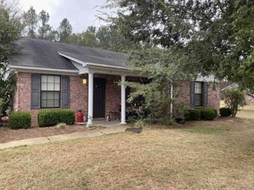 Magee house for rent - a small brick house with a porch and a tree